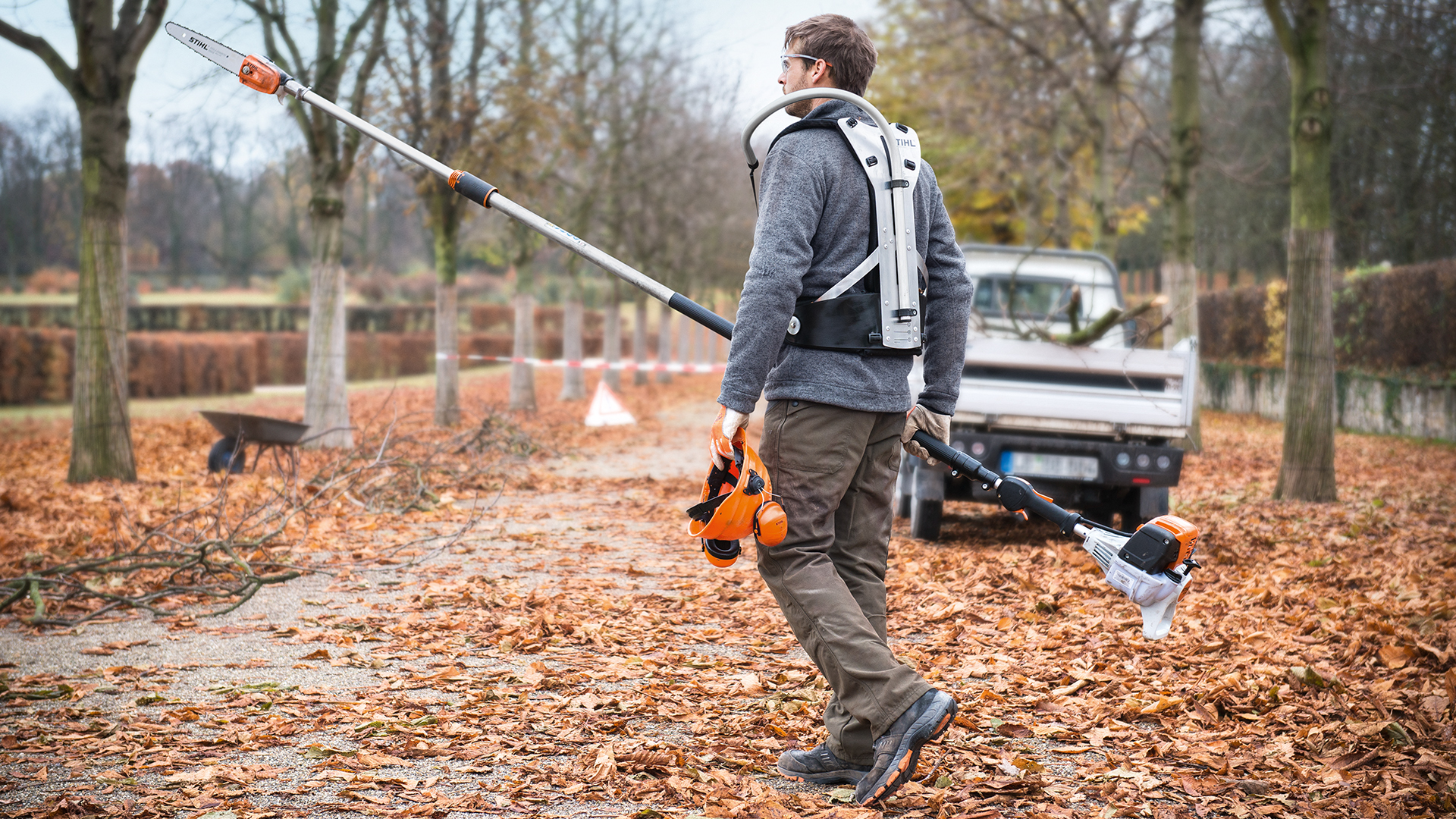 Mann med STIHL HT 133 bensingrensag og arbeidskjøretøy i parken om høsten
