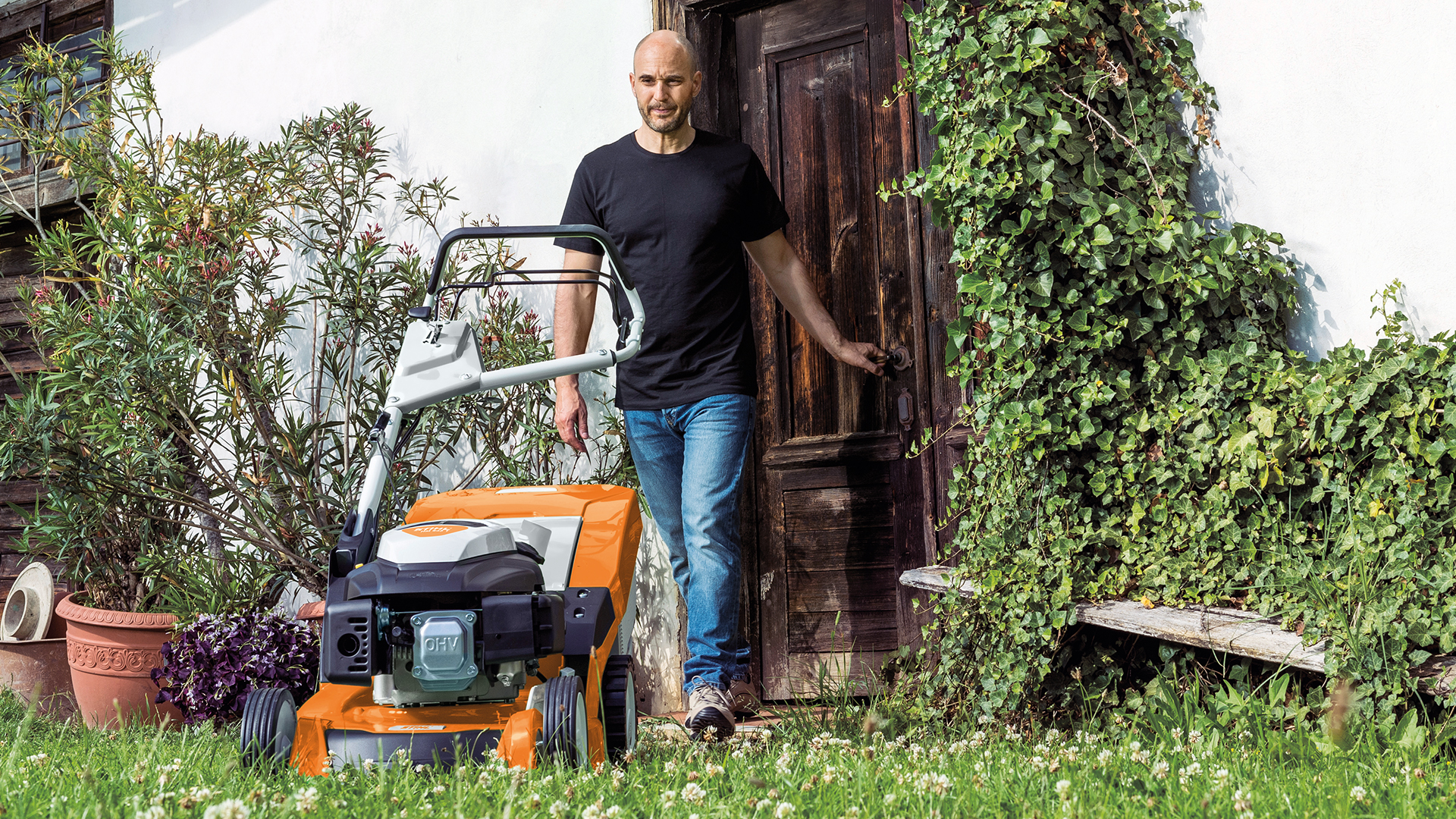 Mannen går mot STIHL bensingressklipper RM 650 i hagen