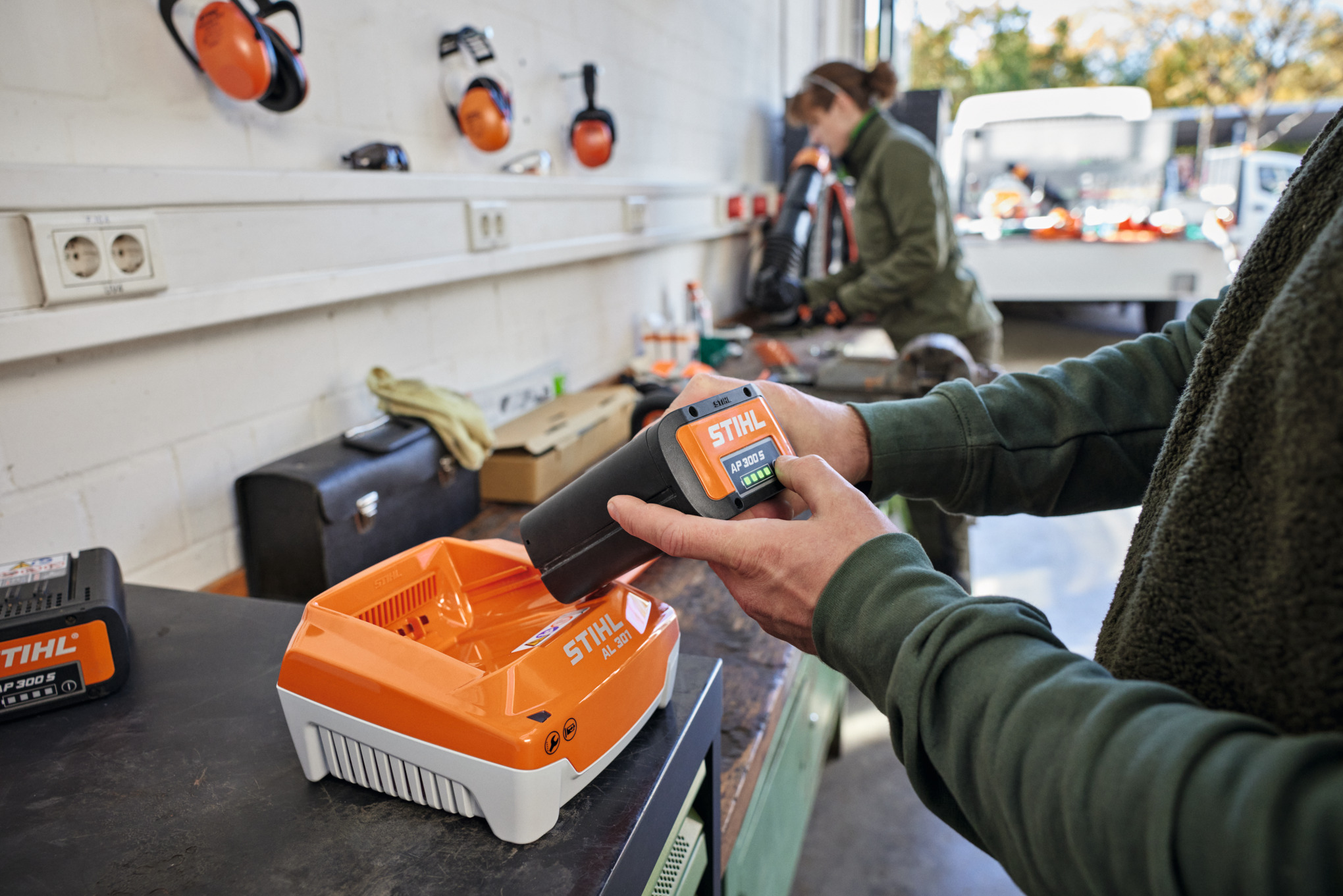 En person setter et STIHL AP 300 S batteri i en STIHL AL 301 hurtiglader