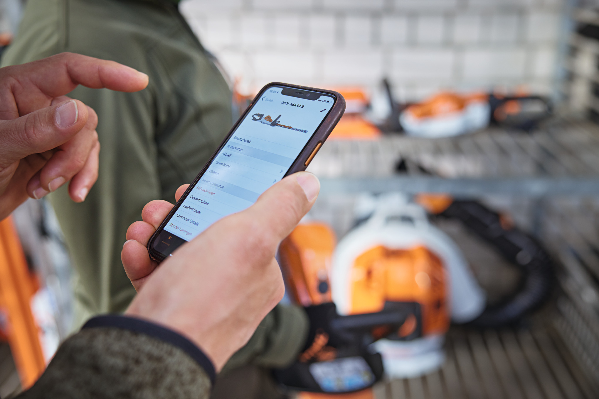 En person med smarttelefon som ser på en motorsag i STIHL Connected-appen