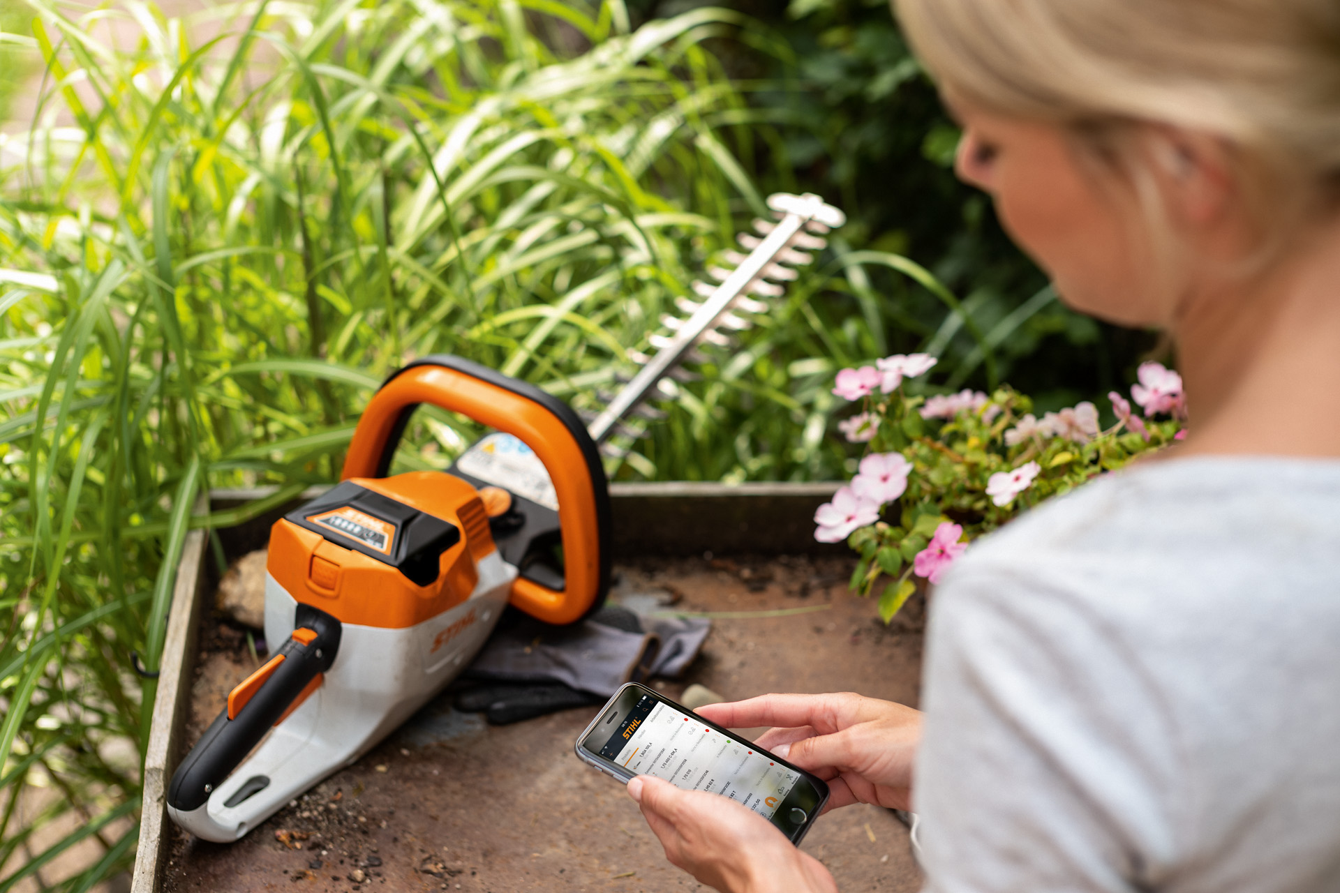 En kvinne registrerer en STIHL hekksaks med STIHL-appen på en smarttelefon