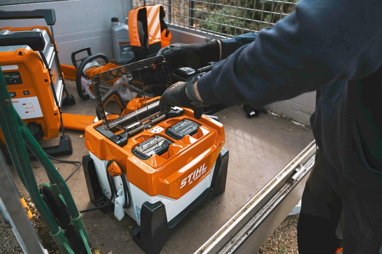 En mann setter inn et ALLPRO-batteri i en hurtiglader