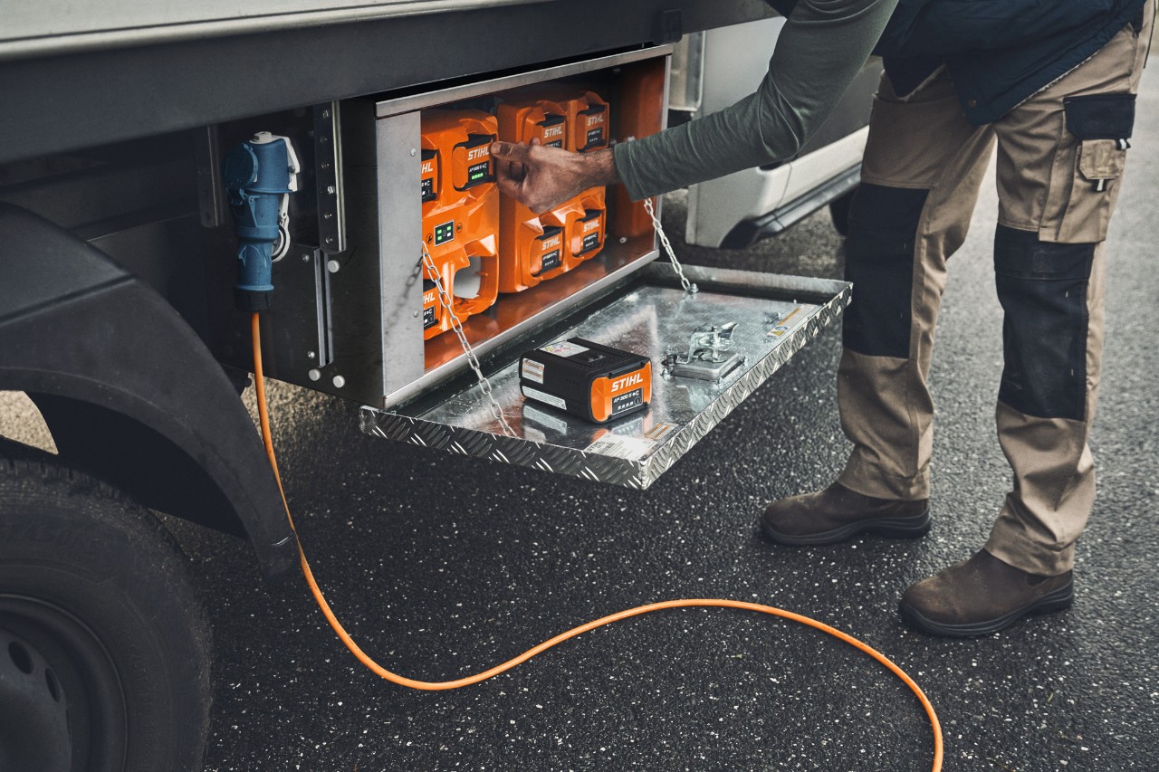 En mann tar et ladet STIHL AP 500-batteri ut av ladeboksen 